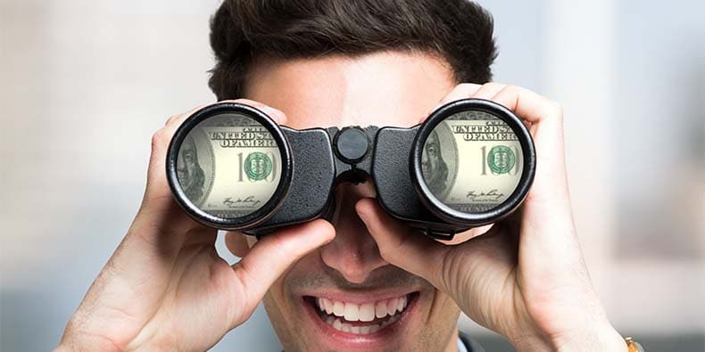 Smiling businessman looking to dollar banknotes through binoculars