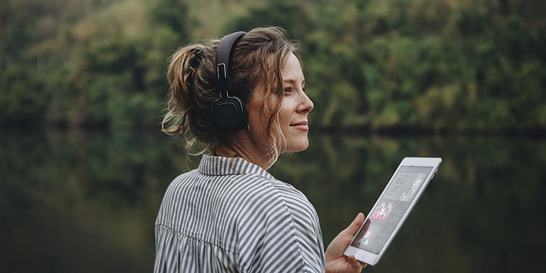 Woman alone in nature listening to music with headphones and digital tablet music and relaxation concept
