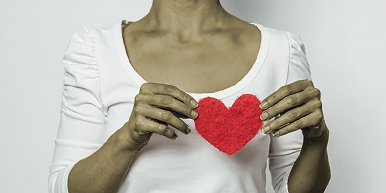 Woman holding fabric heart in front of chest