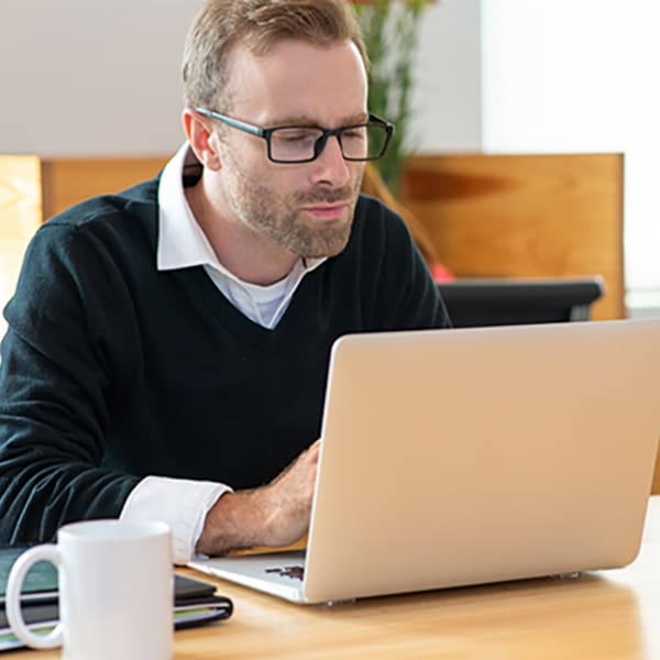 Homme d'affaires d'âge moyen ciblé travaillant sur ordinateur portable. Homme d'affaires assis au bureau avec intérieur de bureau flou en arrière-plan. Concept de travailleur de bureau.