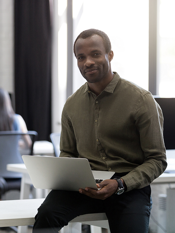 Souriant heureux homme d'affaires américain assis sur son bureau