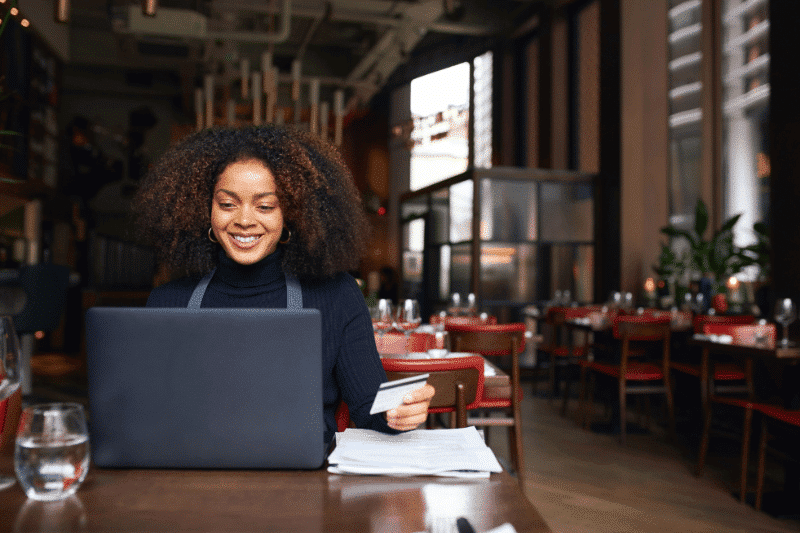 Young woman typing on a laptop in a cafe | The 8 Deadly Wastes: What you Can’t See that’s Silently Killing your Business