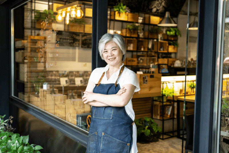 Une femme d'affaires asiatique plus âgée devant son magasin