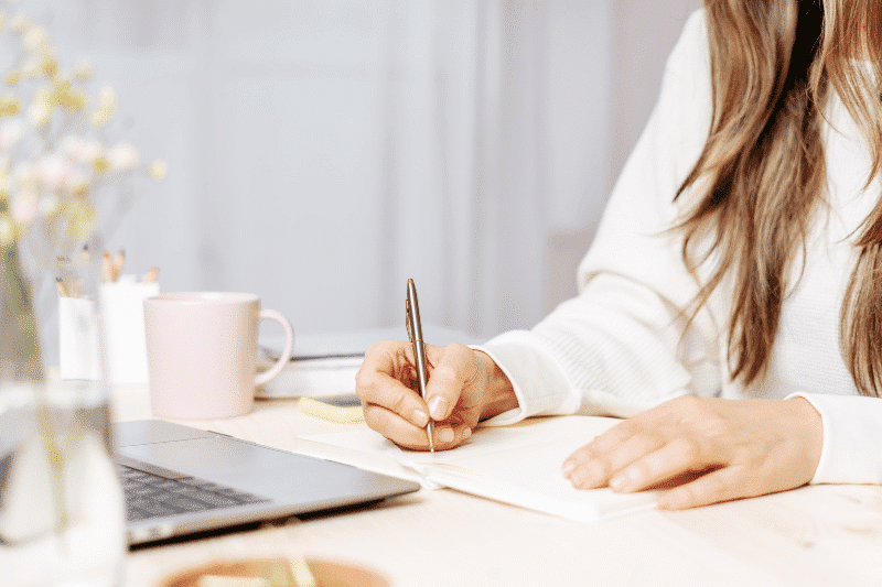 A woman making notes with a laptop and notebook | Business Link Statistics Canada Website
