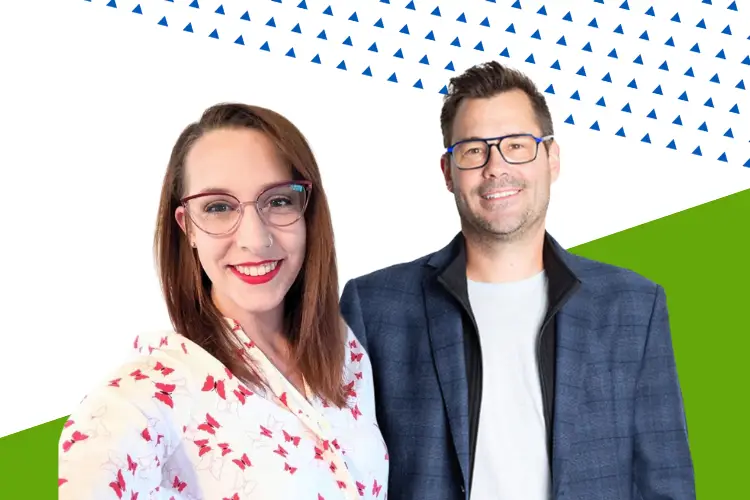 Two smiling professionals standing in front of a modern, geometric background. The woman on the left wears glasses and a white blouse with red floral patterns. The man on the right wears glasses, a navy plaid blazer, and a light gray shirt.