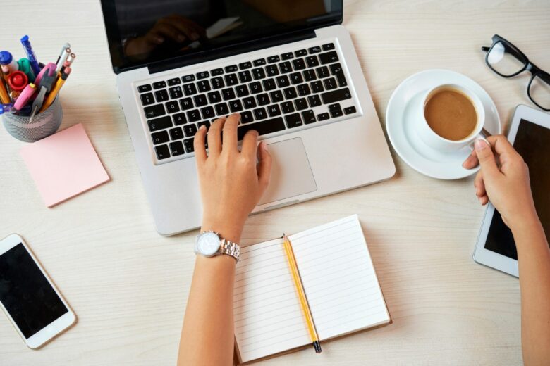 Digital marketing workspace with a laptop, tablet, phone, coffee and handwritten notes.