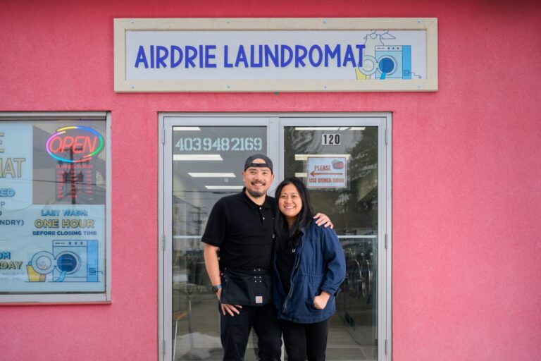 Karla and Fil Rodriguez standing in front of their Airdrie Laundromat storefront.